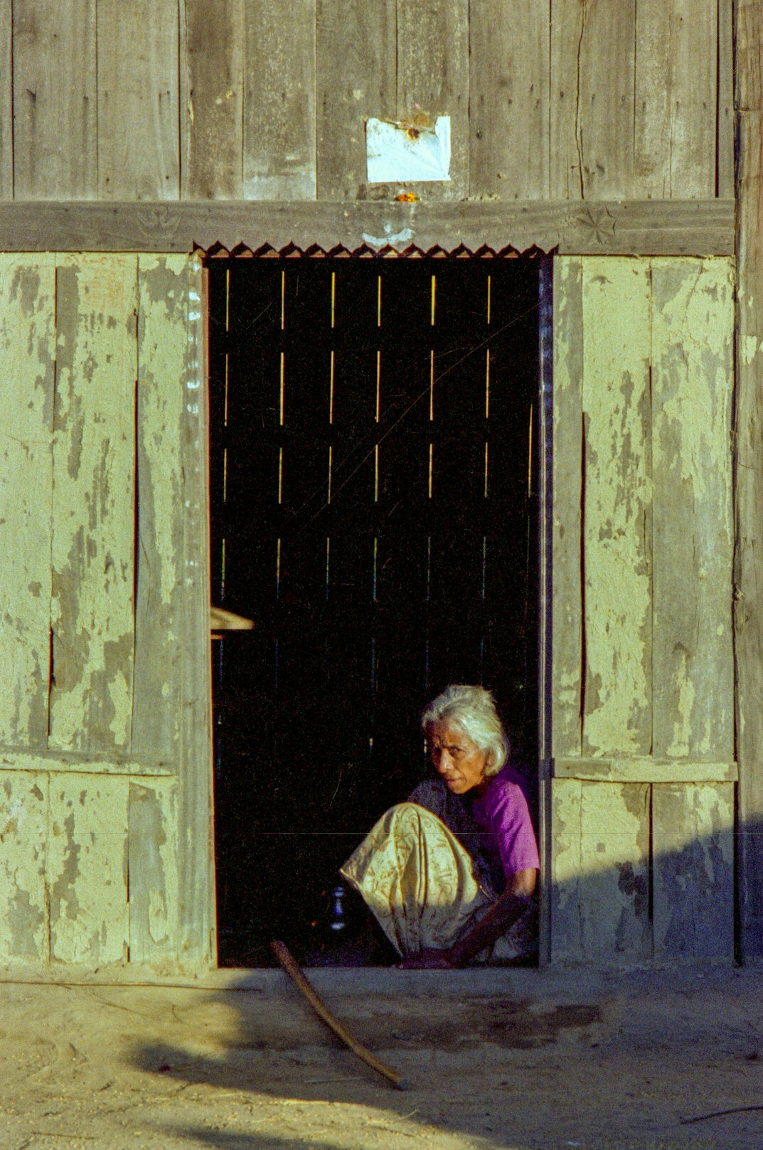 Elderly Polish woman standing in a doorway of a wooden house
